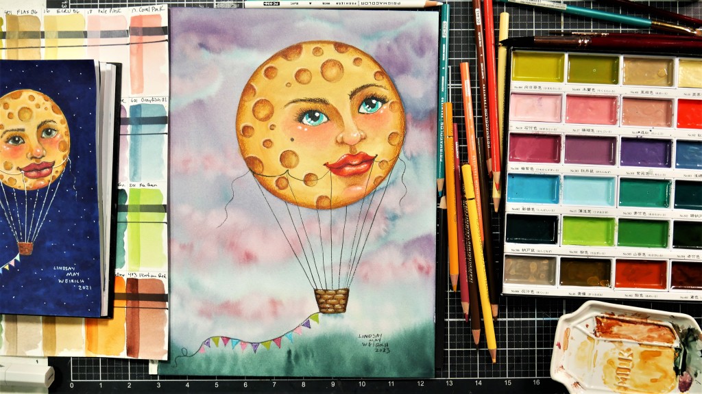Watercolor painting of a hor air ballon and watercolors on a desk.